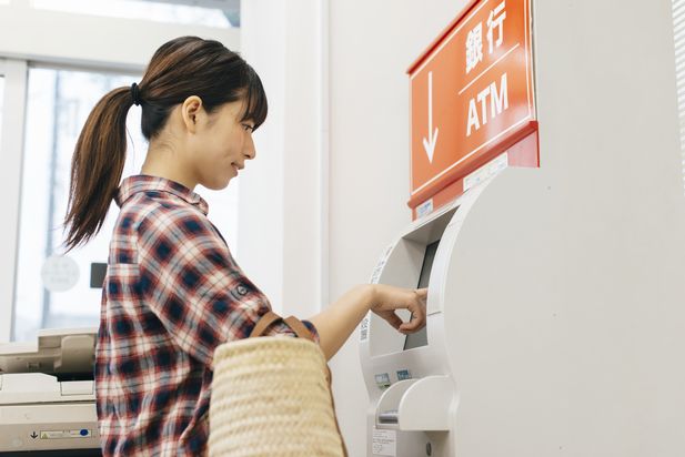 コンビニ設置の銀行ATMから返済する女性